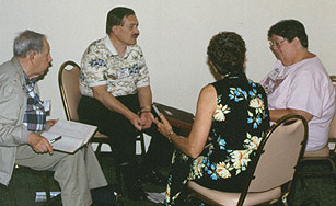 Three members of the auditing committee huddle around Virgil working