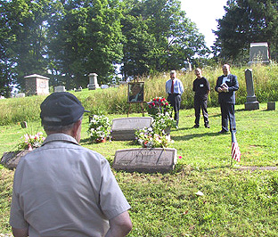Several men stand by a grave